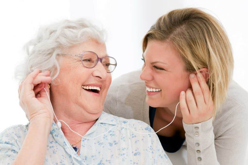 Two women young and old laughing and listening to headphones