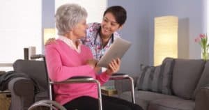 Old woman on a wheelchair conversing with a nurse